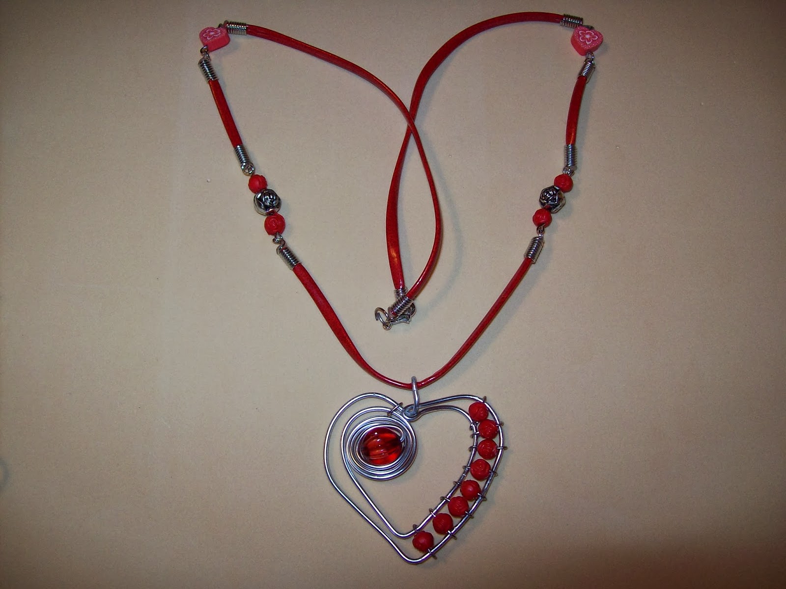 Collar artesanal con cordón rojo y colgante de corazón en alambre plateado con cuentas rojas