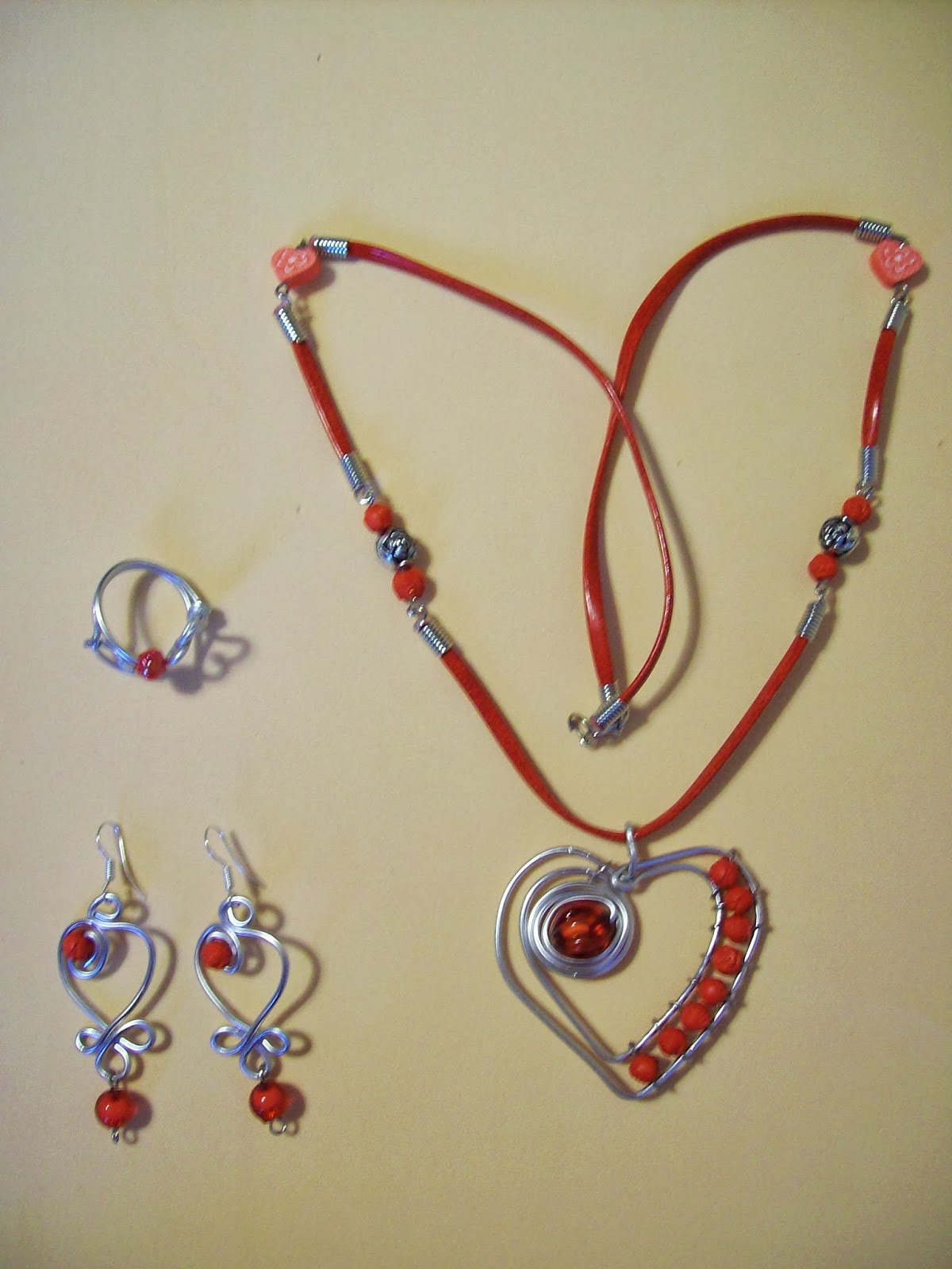 Conjunto de joyería artesanal a juego con collar de corazón, pendientes y anillo en tonos rojos y plateados